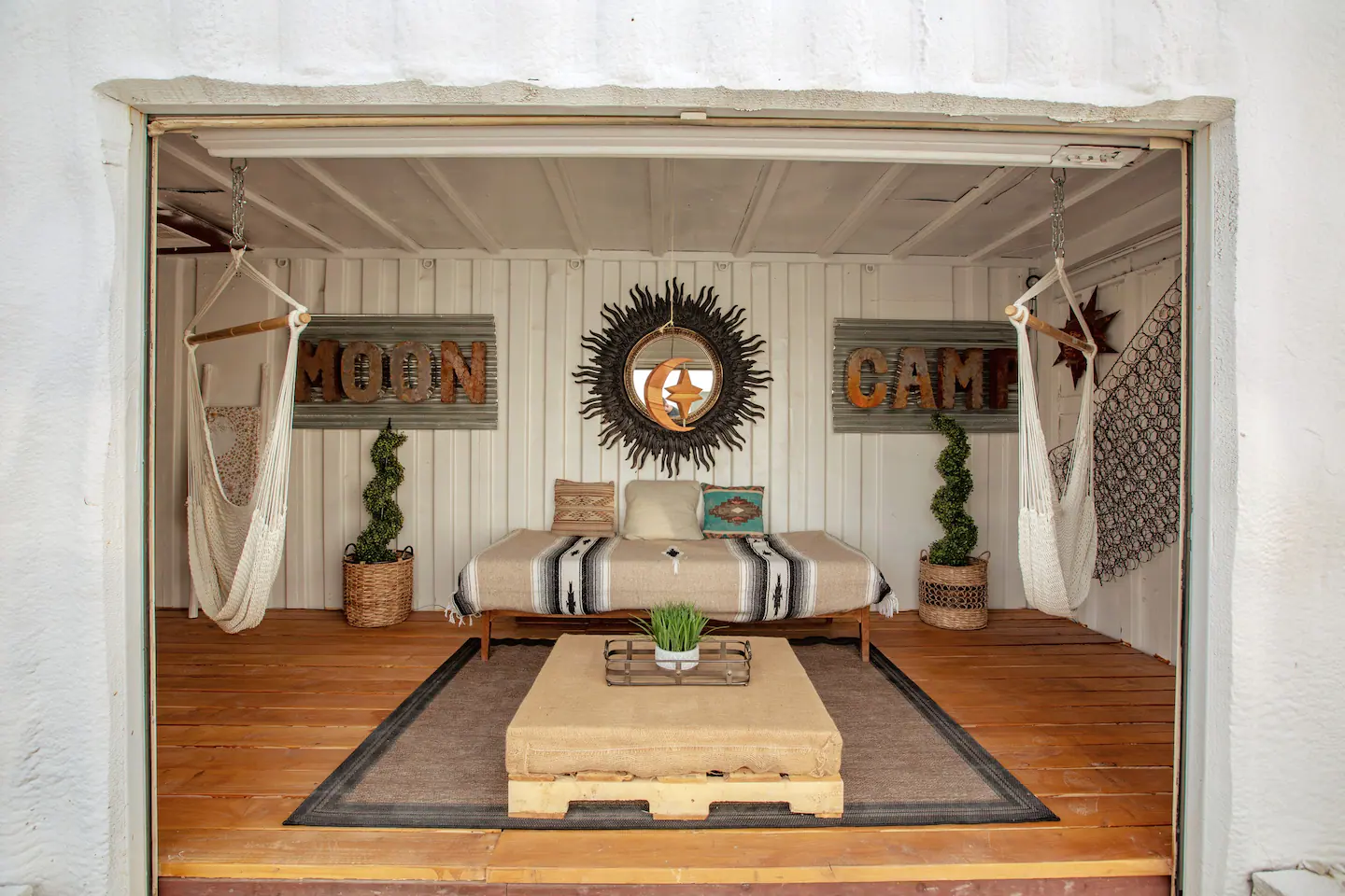 The freshly remodeled "Area 51" shipping container lounge living room at Moon Camp features a daybed and two swinging hammock chairs. Relax among the stars!