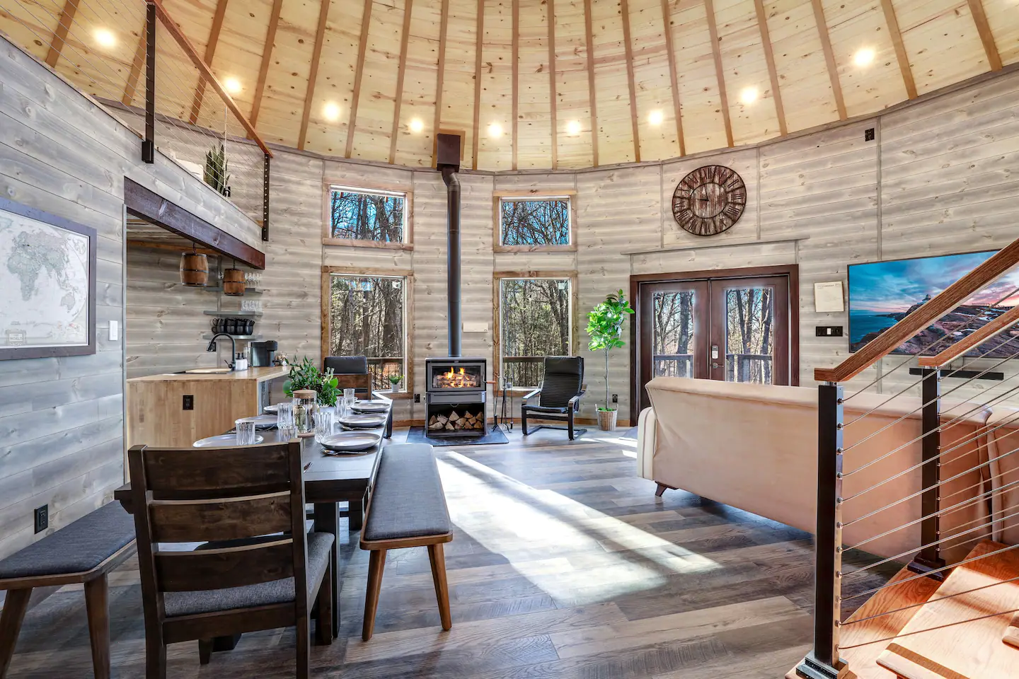 A wood-burning heater, an extensible dining table, a pin map, and rocking chairs.