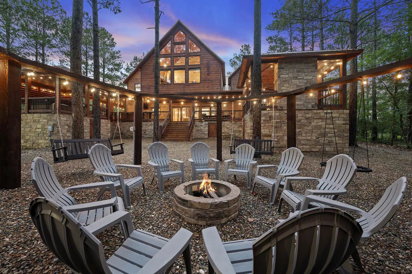The fire pit offers ample seating with four benches accommodating three people each, along with individual swings. It is conveniently positioned adjacent to a custom playset.