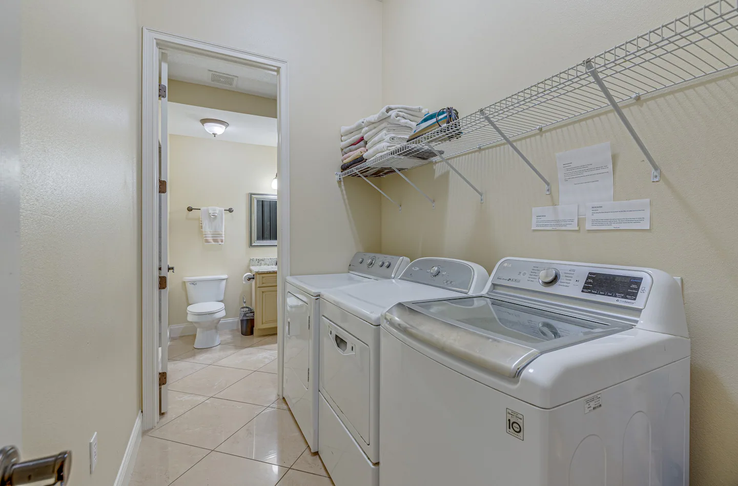 Laundry room equipped with a washer and two dryers.