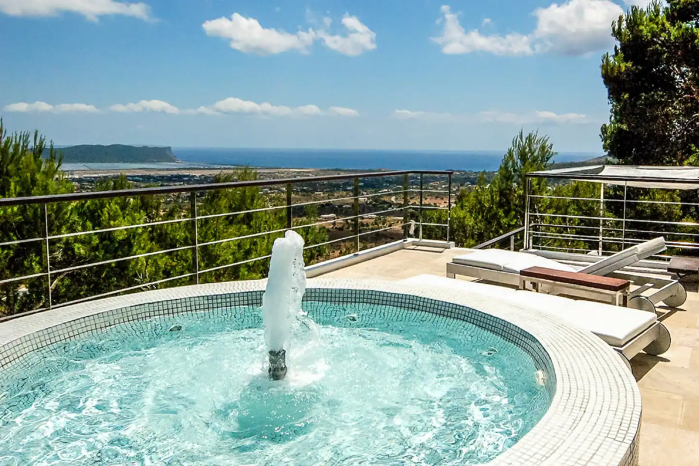 An idyllic outdoor hot tub area with steaming water, surrounded by nature, and a view of the starry night sky
