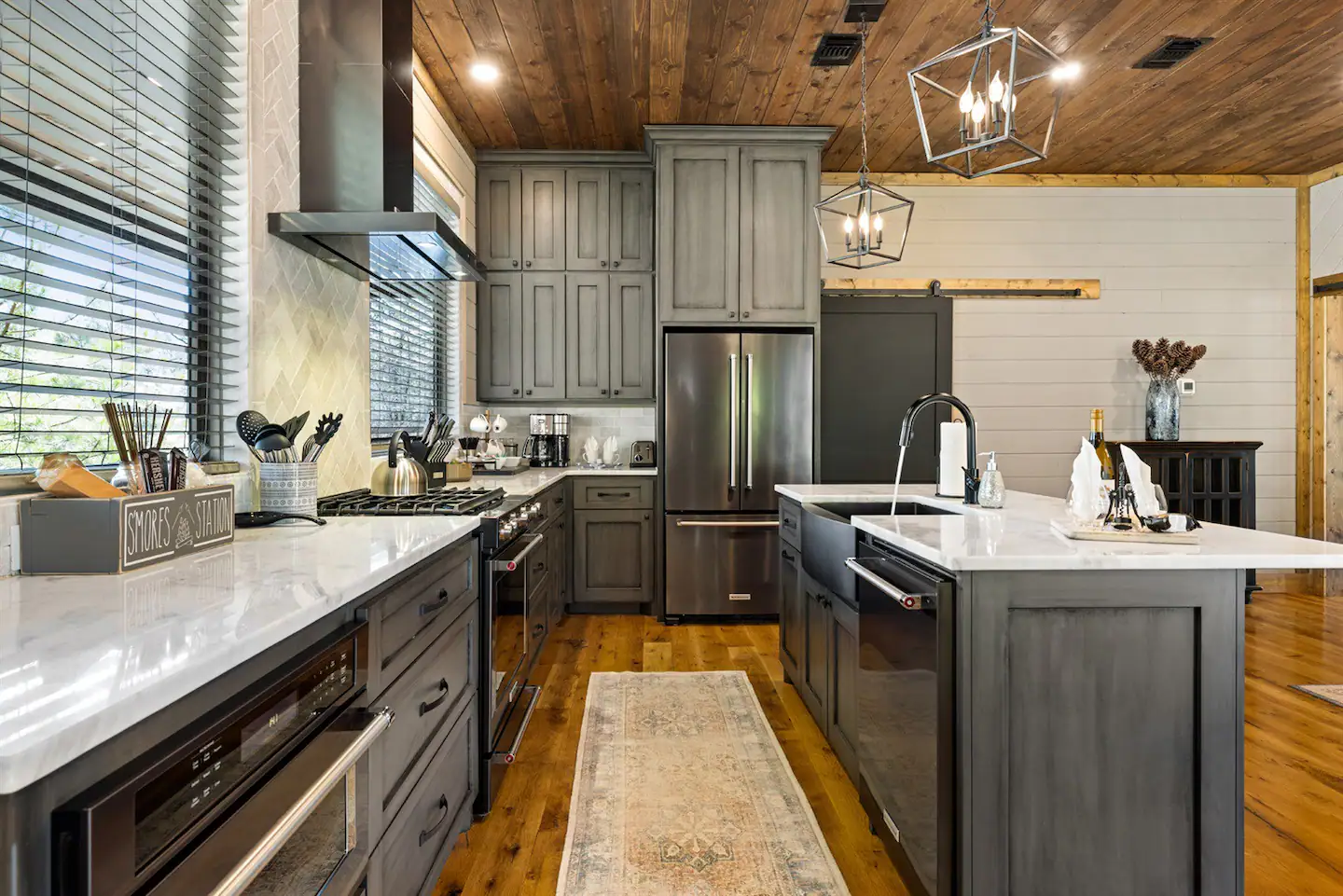 This fully equipped kitchen is made up of all black stainless-steel Kitchen Aid appliances and marble counter tops.