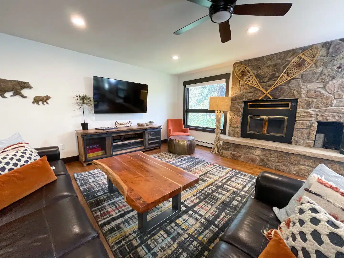 The vast living room provides ample seating, facing the fireplace and outdoors with views of the river from the windows.